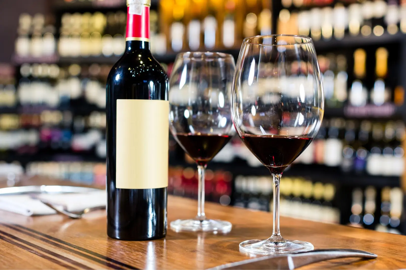 Botella de vino tinto y dos copas servidas en la barra