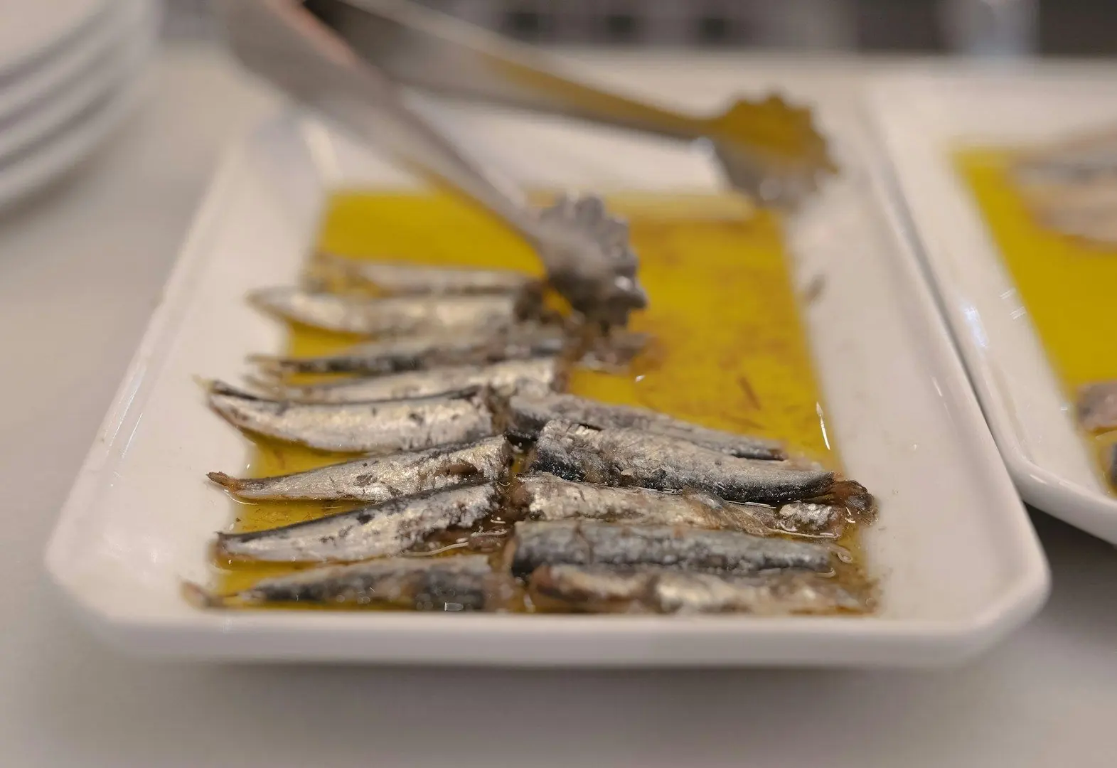 Boquerones en aceite de oliva servidos en fuente blanca